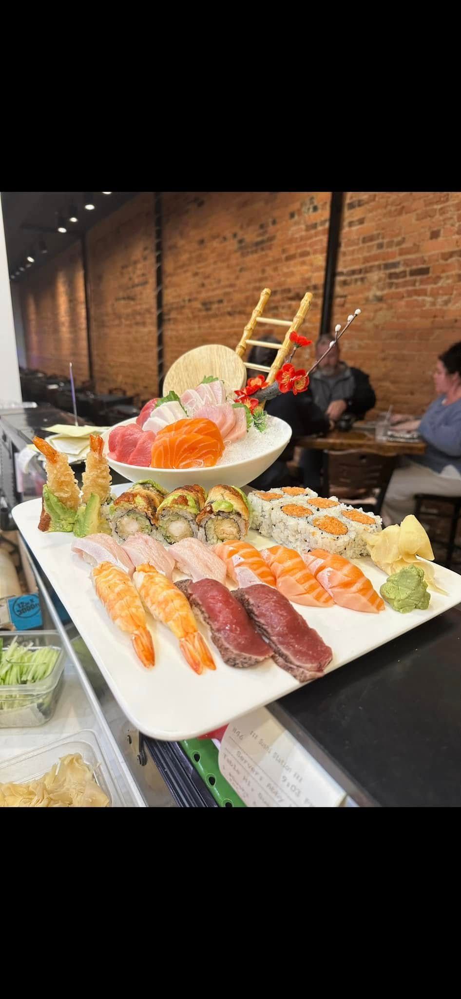 Sushi platter with various nigiri and rolls displayed in a restaurant setting.
