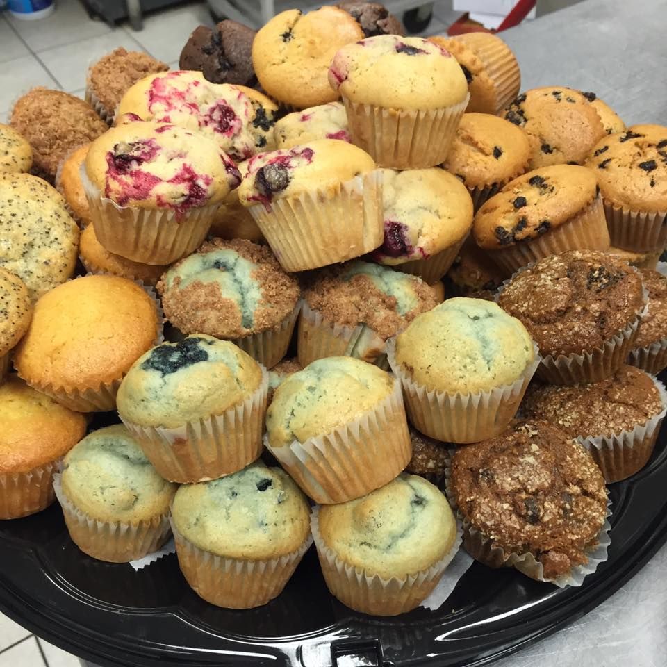 A Variety Of Muffins Are Stacked On Top Of Each Other On A Black Plate - Mahopac, NY - Our Town Bagels & Bakery