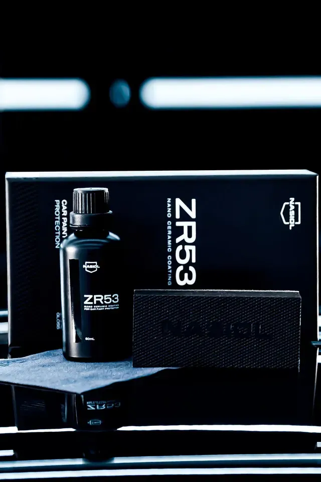 A black box and bottle of ZR53 nano ceramic coating with an applicator pad, set against a dark, reflective surface.