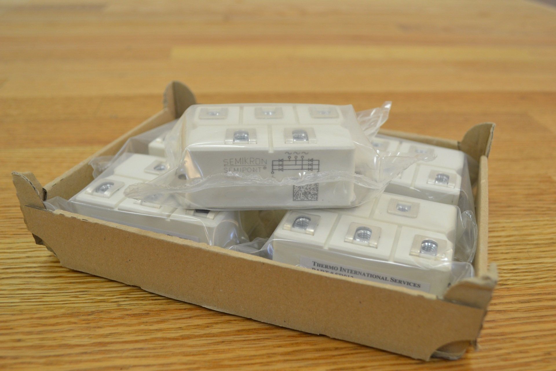 A cardboard box filled with white blocks is sitting on a wooden table.