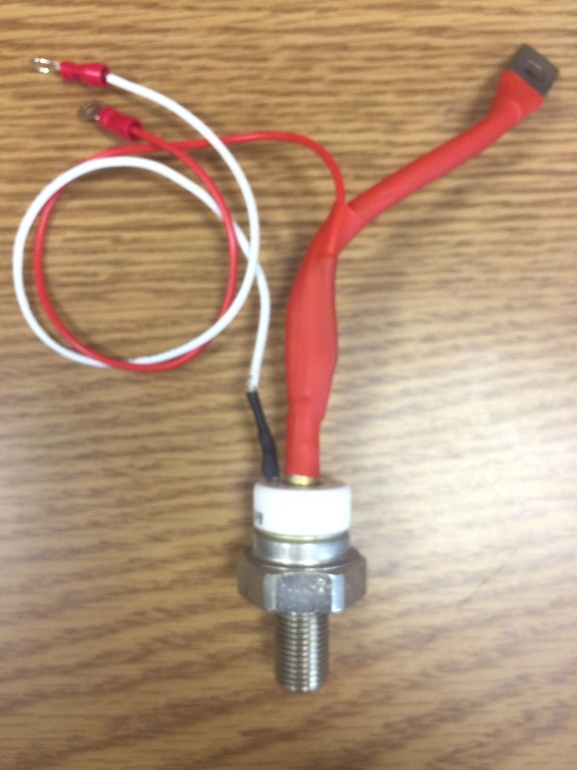 A red and white wire is attached to a metal object