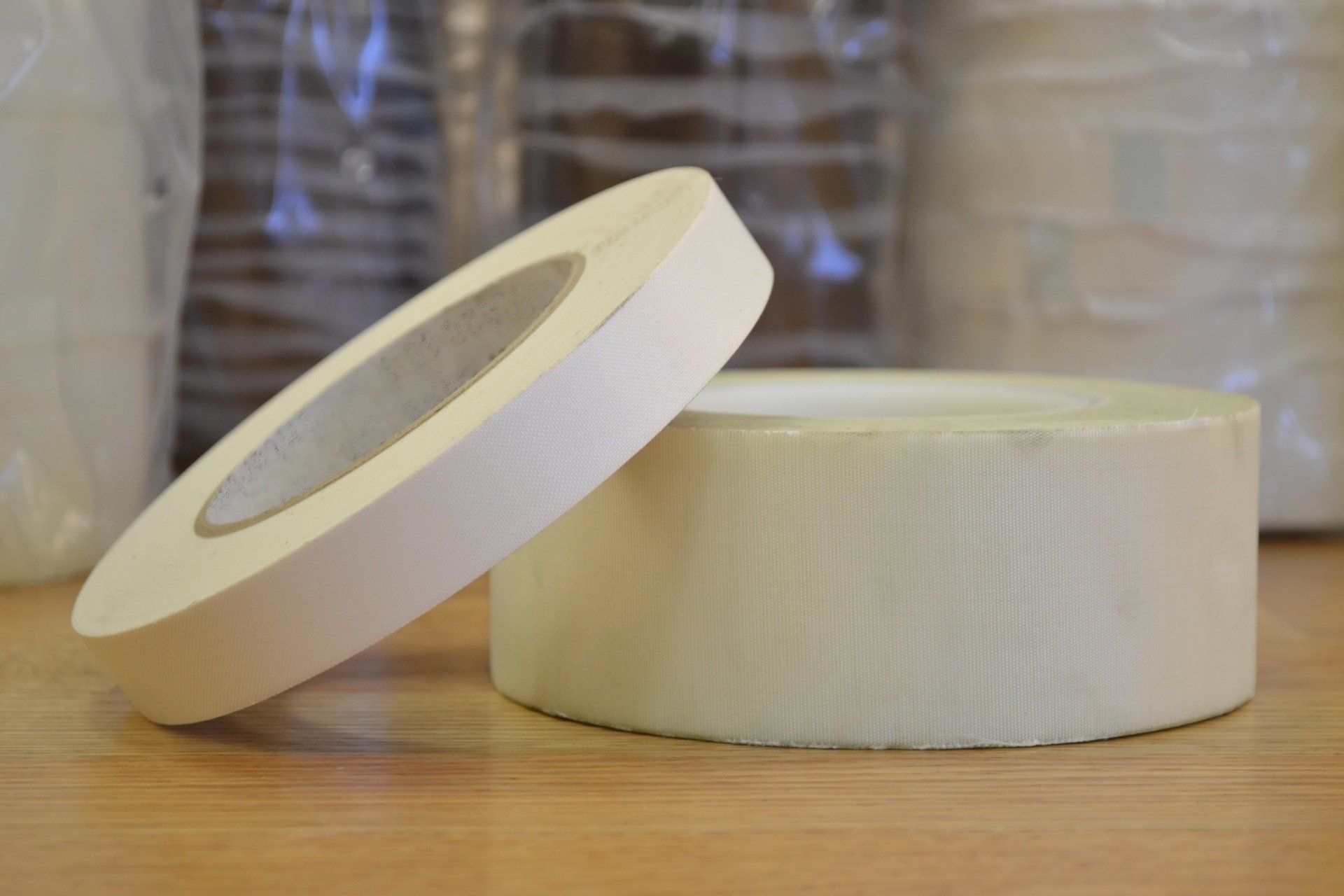 Two rolls of white tape are sitting on a wooden table.