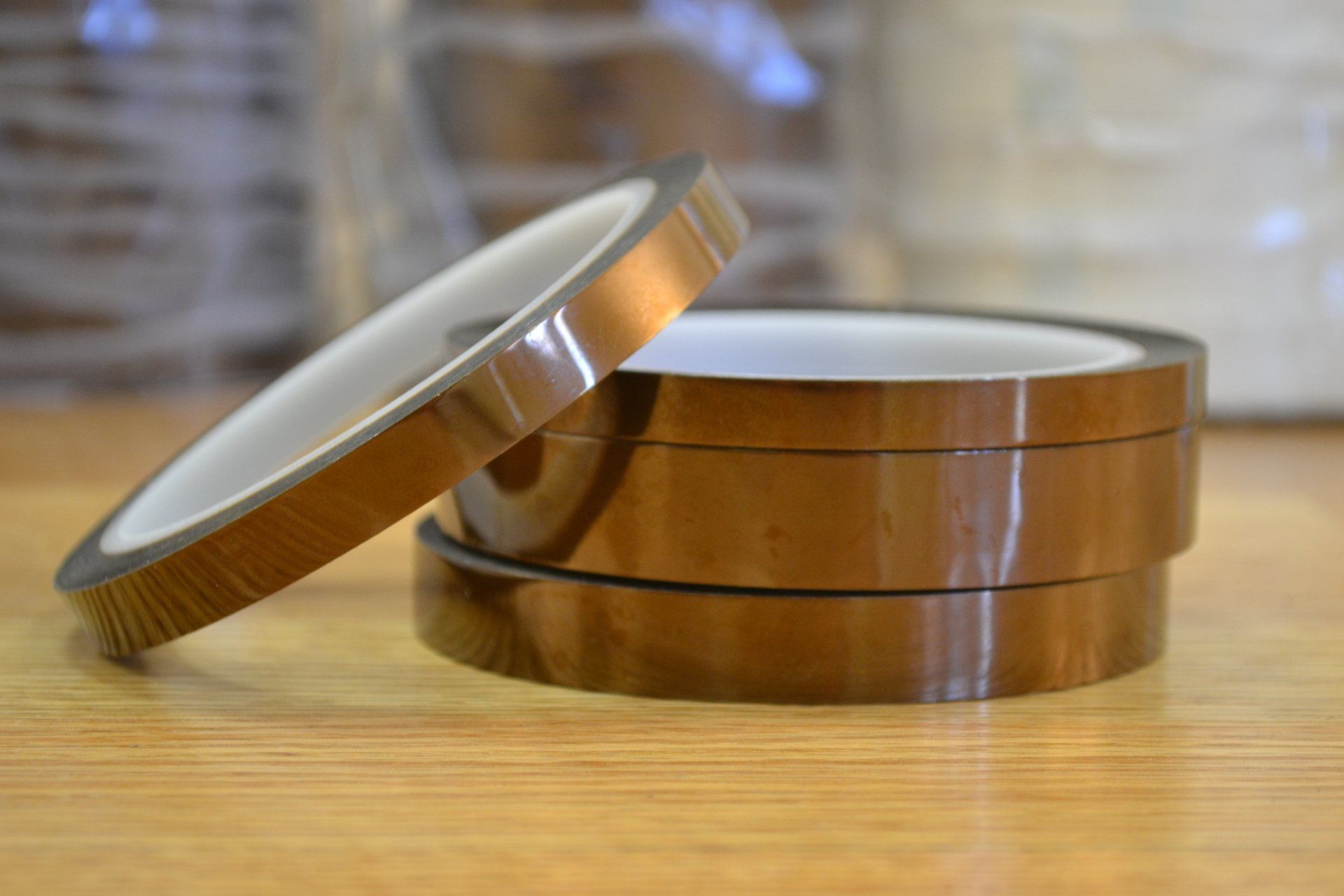 Three rolls of brown tape are stacked on top of each other on a wooden table.