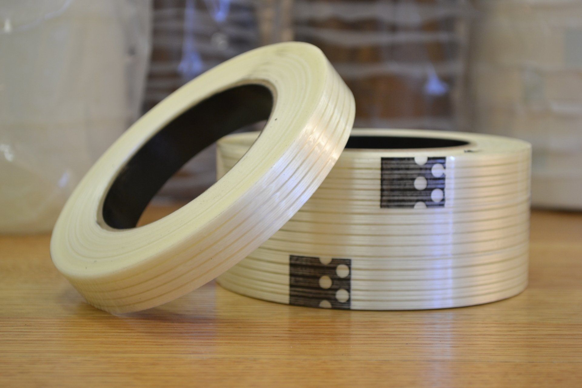 Two rolls of tape are sitting on a wooden table.