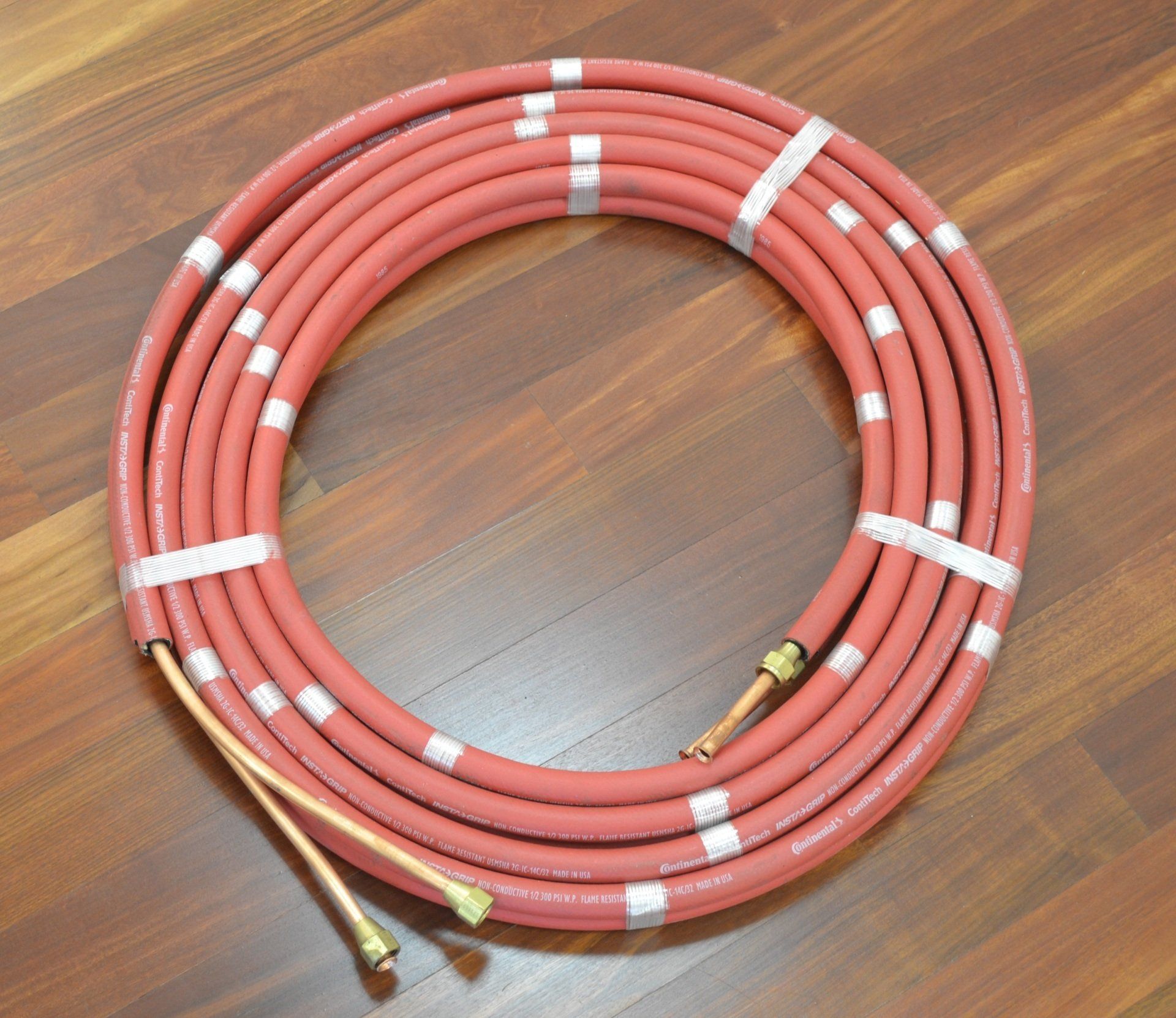 A red hose is laying on a wooden floor