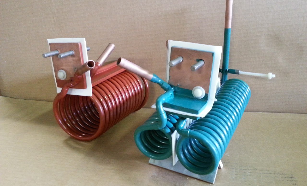 Two industrial coil, one red and one teal, positioned side-by-side against a plain brown background.