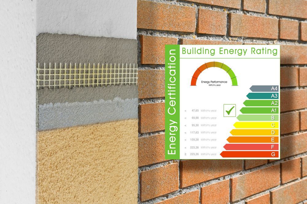 Etichetta di classificazione energetica dell'edificio accanto alla sezione trasversale di una parete in mattoni isolata.