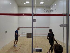 A man and a woman are playing squash in squash court 1