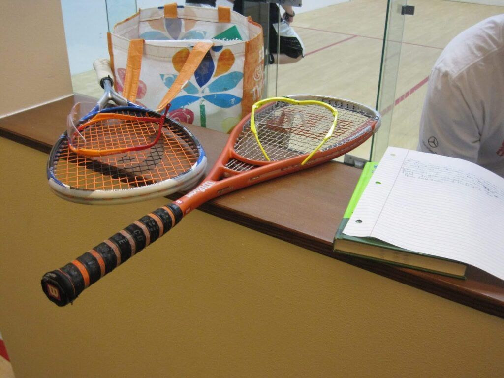 Two tennis rackets are on a table next to a notebook and a bag