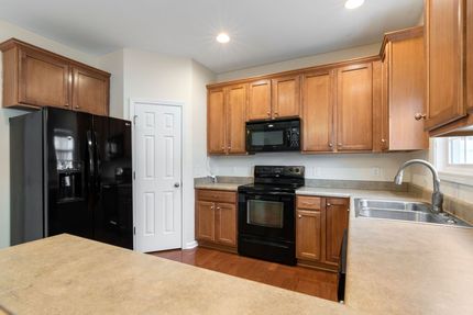 Modern kitchen with black appliances, wood cabinets, and beige countertops