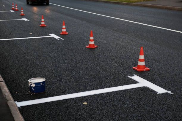 Road with orange traffic cones and white lane markings near a small paint can