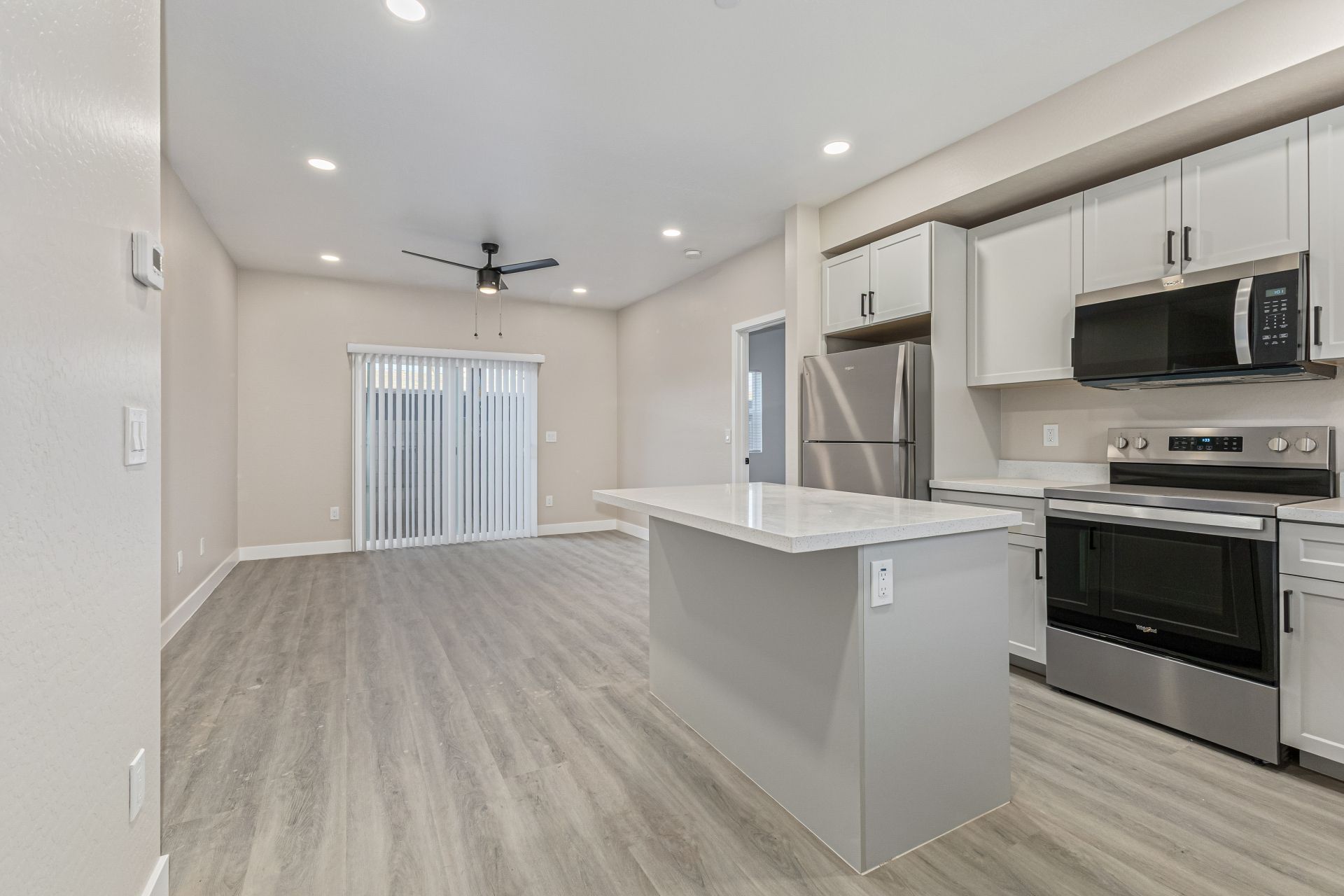 Bright living area with ceiling fan, recessed lighting, and kitchen island with sink