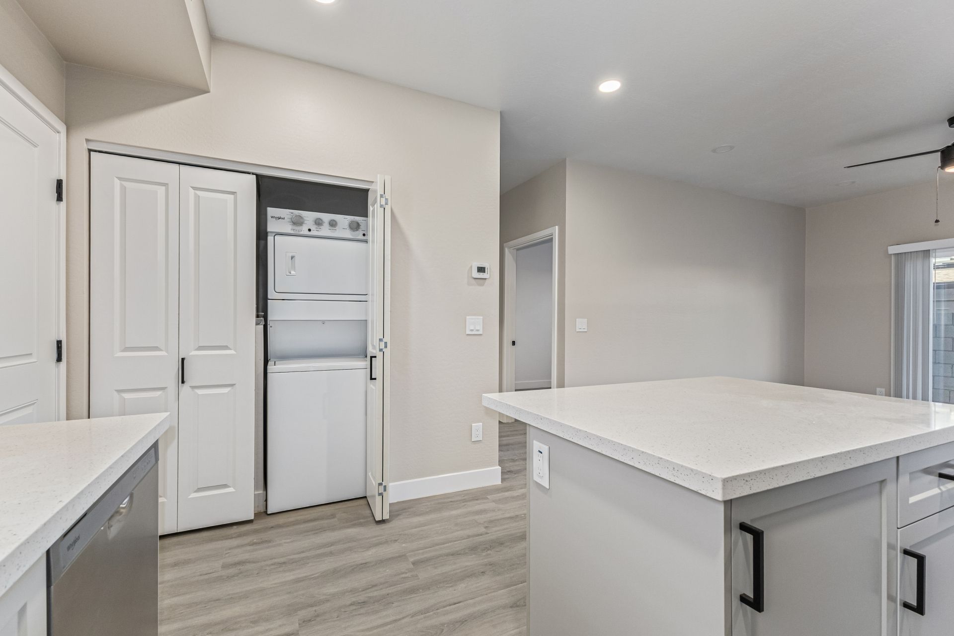 Modern kitchen with quartz island and in-unit stacked washer and dryer in closet