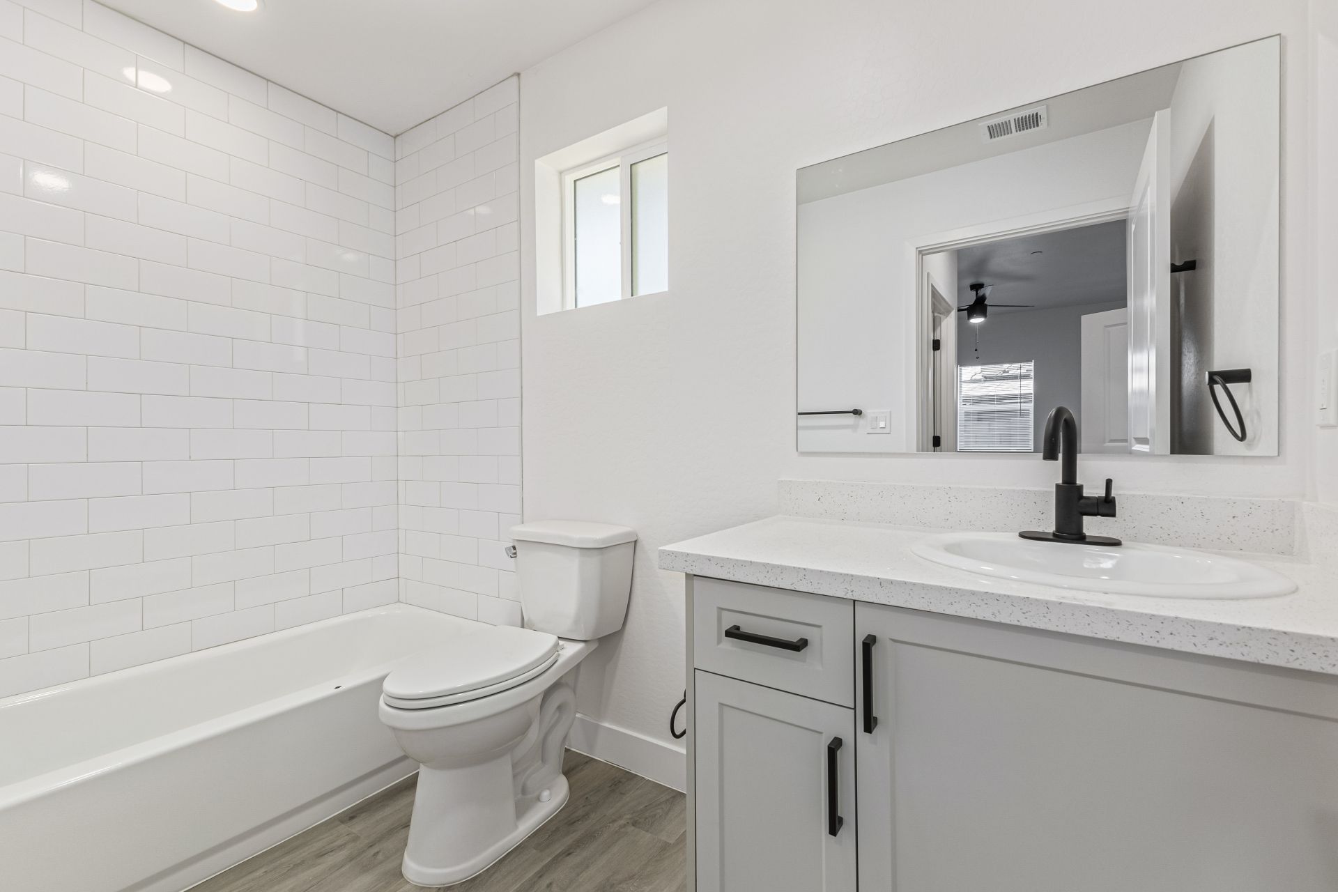 Modern bathroom with white subway tile shower, quartz vanity, and matte black fixtures