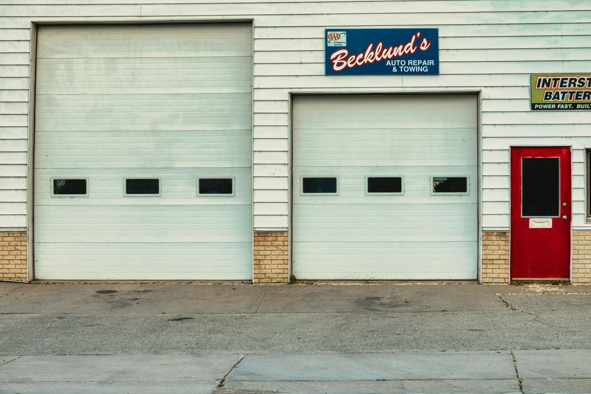 White garage doors on a building with signs for 