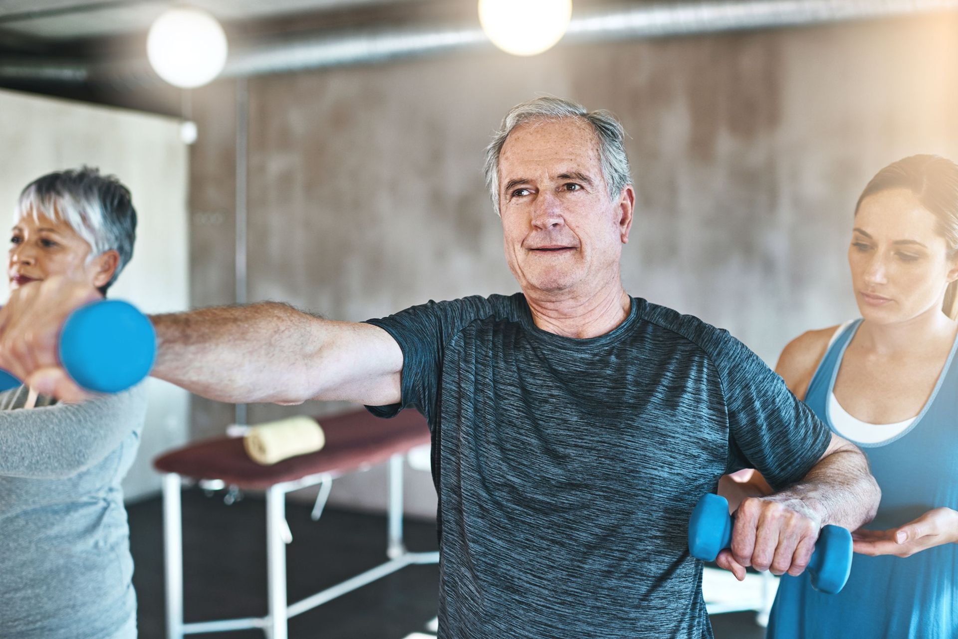 A group of people are lifting dumbbells in a gym.