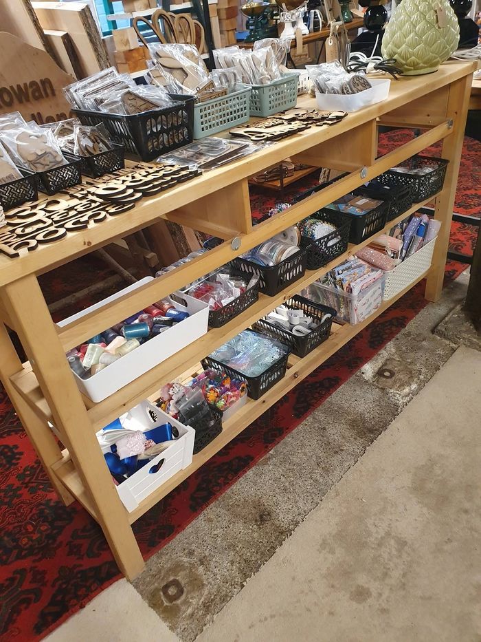 Wooden display shelf with assorted wrapped soaps and small gift items in a store.