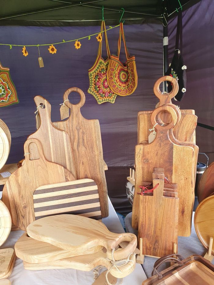 Handmade wooden chairs and baskets displayed at an outdoor market stall