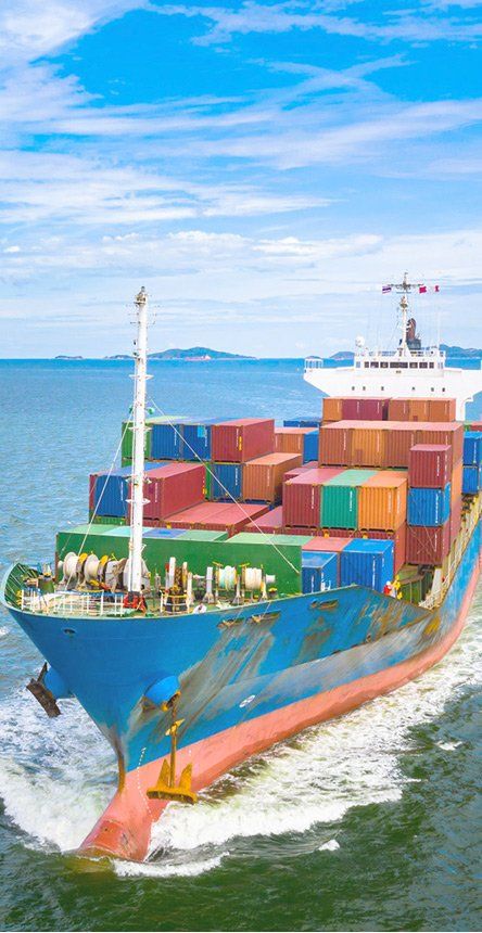 Een vrachtschip volgeladen met kleurrijke containers vaart op blauw water onder een heldere hemel.