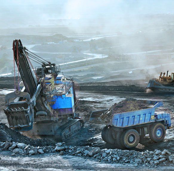 Een graafmachine en een blauwe kiepwagen werken in een rotsachtige open mijn onder een wazige hemel.