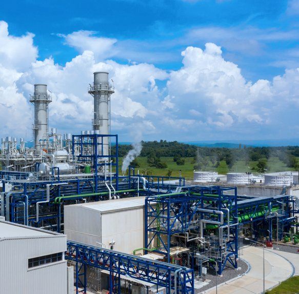 Industriële installatie met blauwe leidingen en witte torens onder een bewolkte hemel.