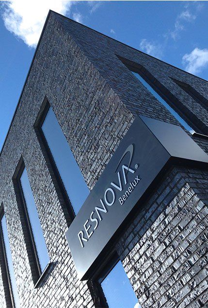 Modern gebouw van zwarte baksteen met blauw omlijste ramen en een bord met de tekst 