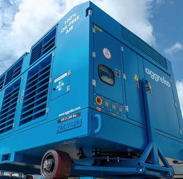 Blauwe industriële generator op een aanhanger tegen een bewolkte hemel.