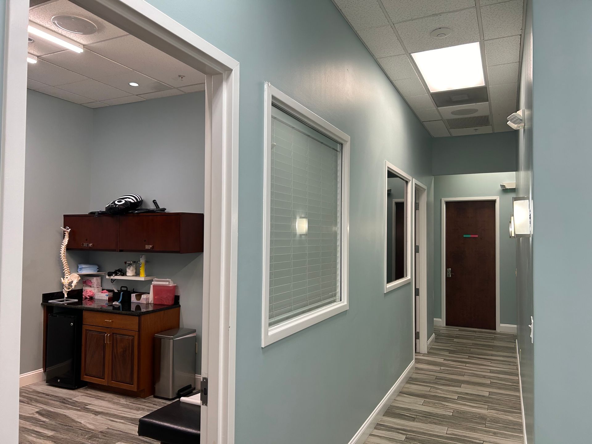 A hallway in a medical office with blue walls and windows.