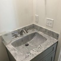 A bathroom sink with a marble counter top and faucet.