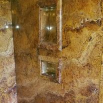 A shower stall with a marble wall and a glass door.