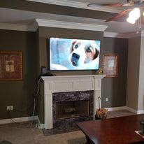 A living room with a fireplace , television , and ceiling fan.