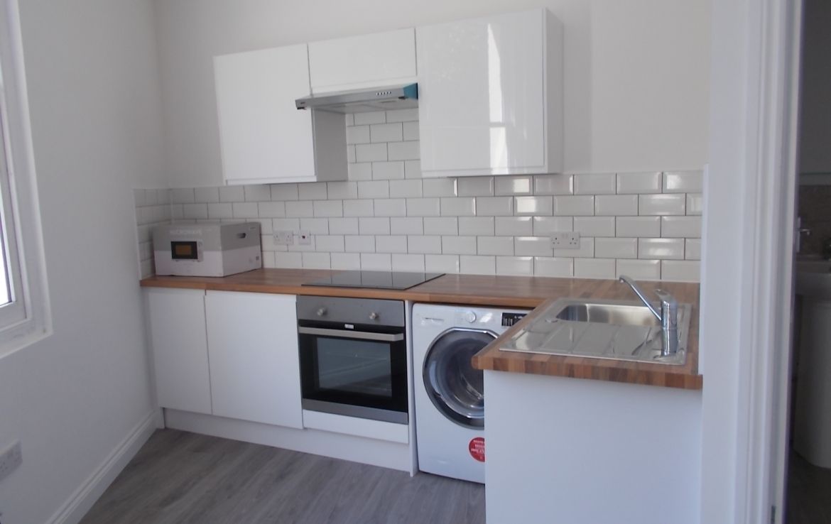 a kitchen with white cabinets and a washer and dryer