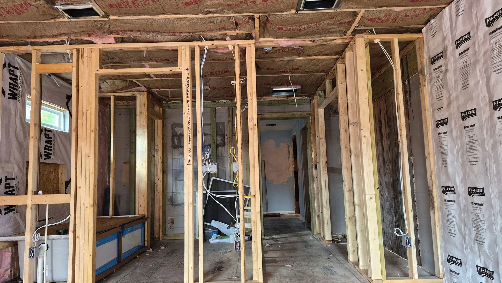 Unfinished interior with exposed wooden framing and insulation in a narrow hallway room.