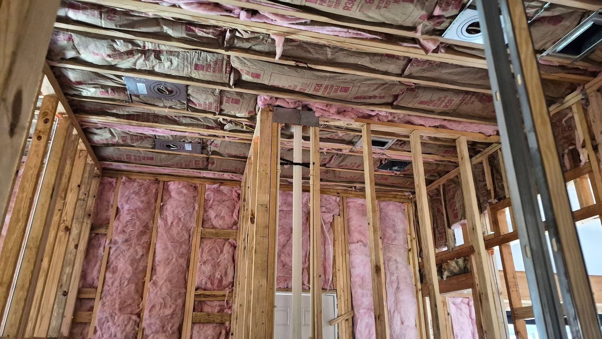 Insulated unfinished wall and ceiling framing in a house under construction