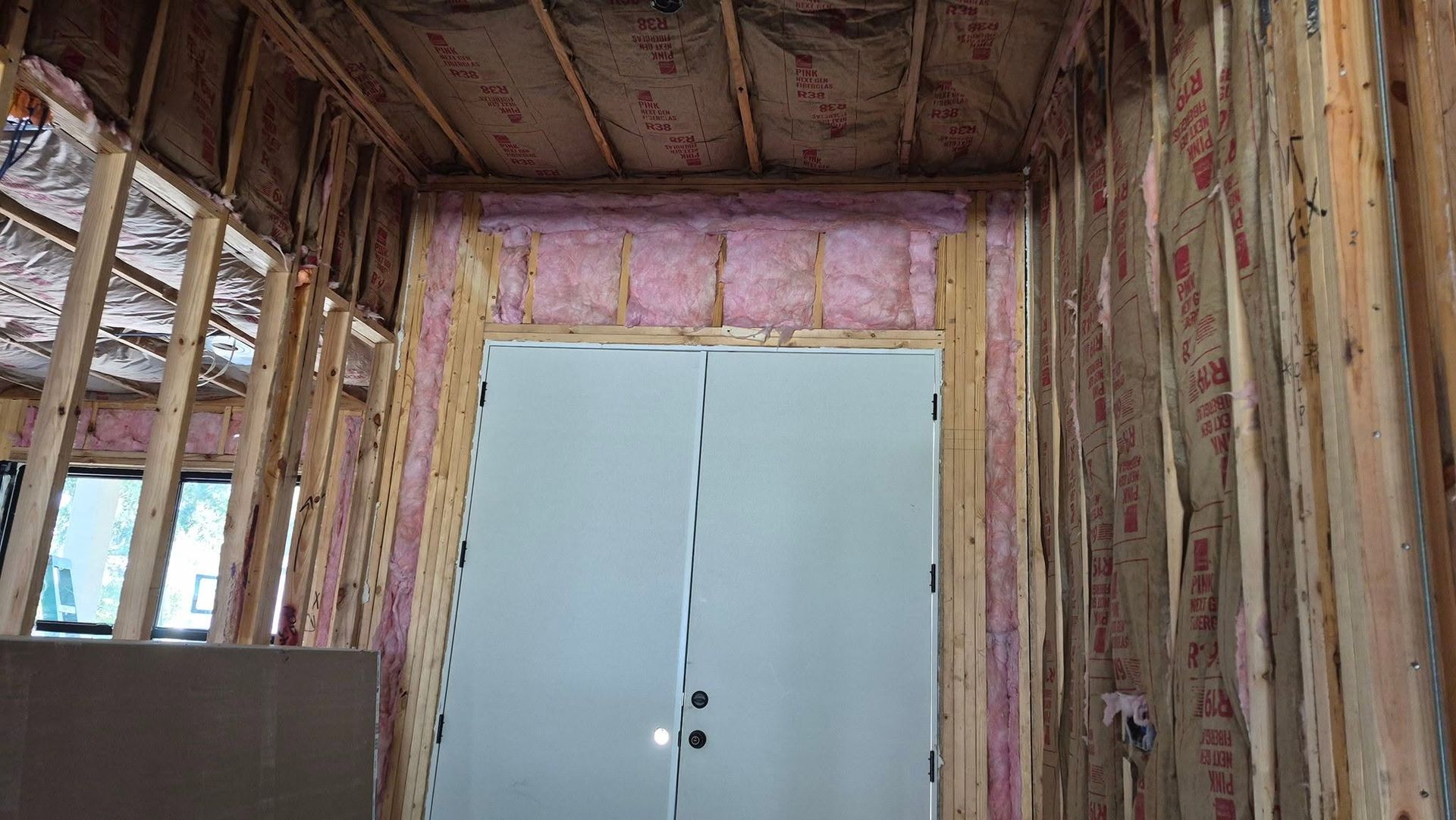 Exposed wall framing around white double closet doors in an unfinished room
