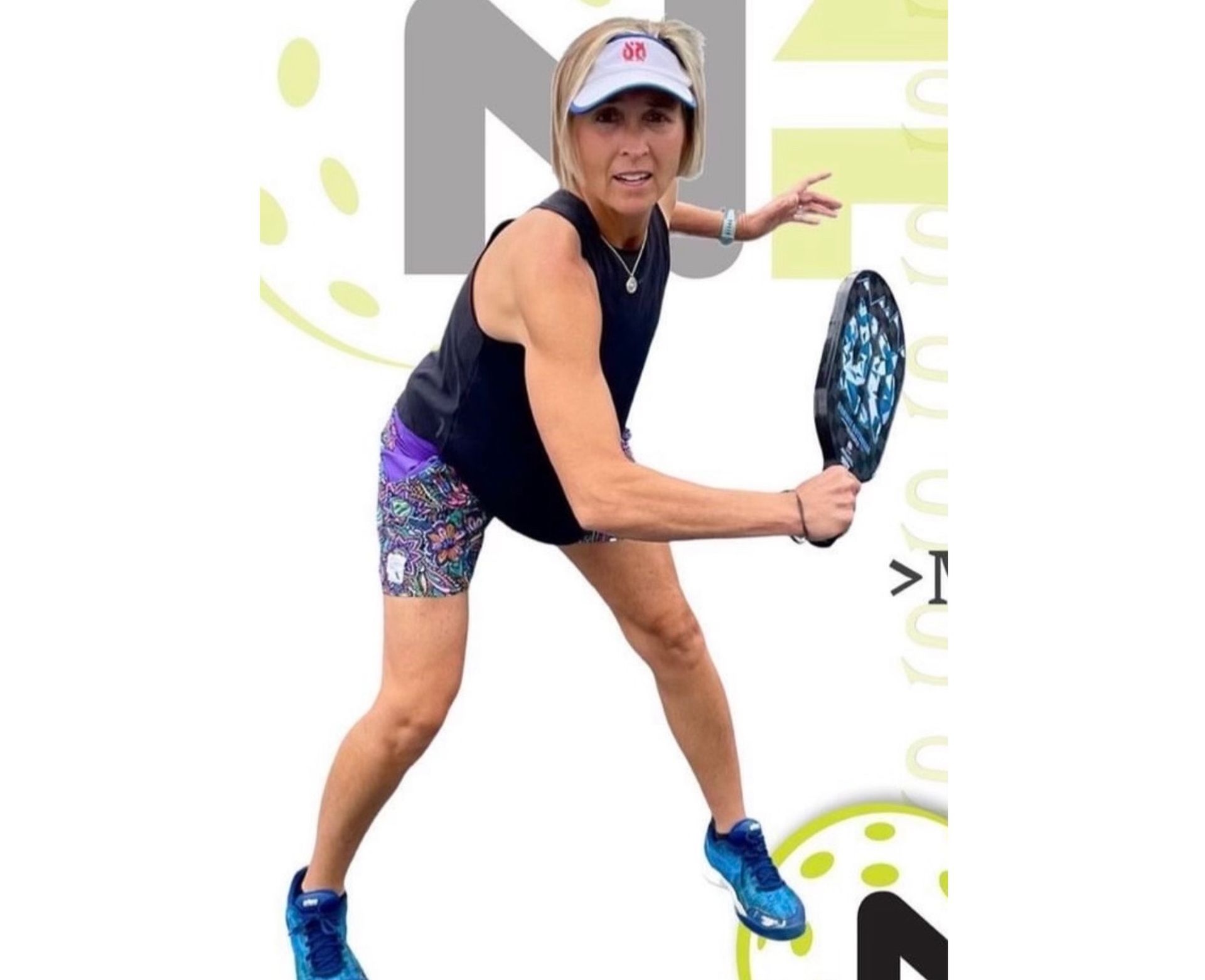 Woman playing pickleball, wearing visor, holding paddle, on court, in athletic wear.