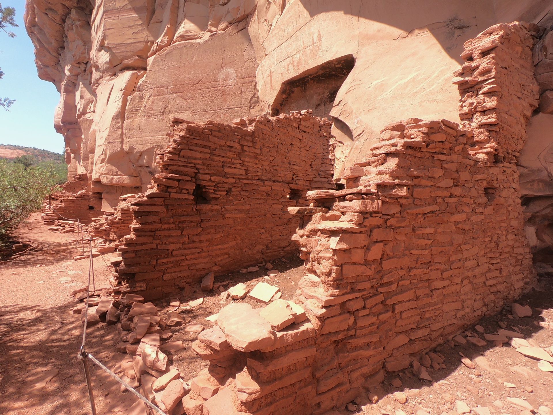 A brick wall with a hole in it is surrounded by rocks.