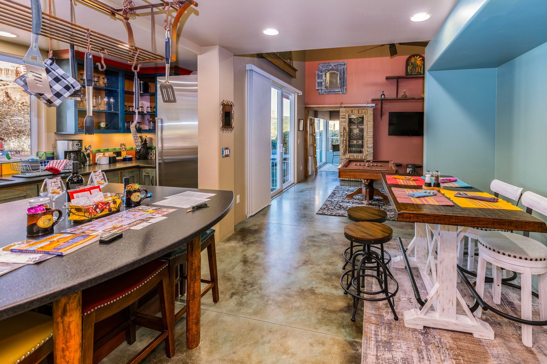 A kitchen with a long table and stools and a pool table.
