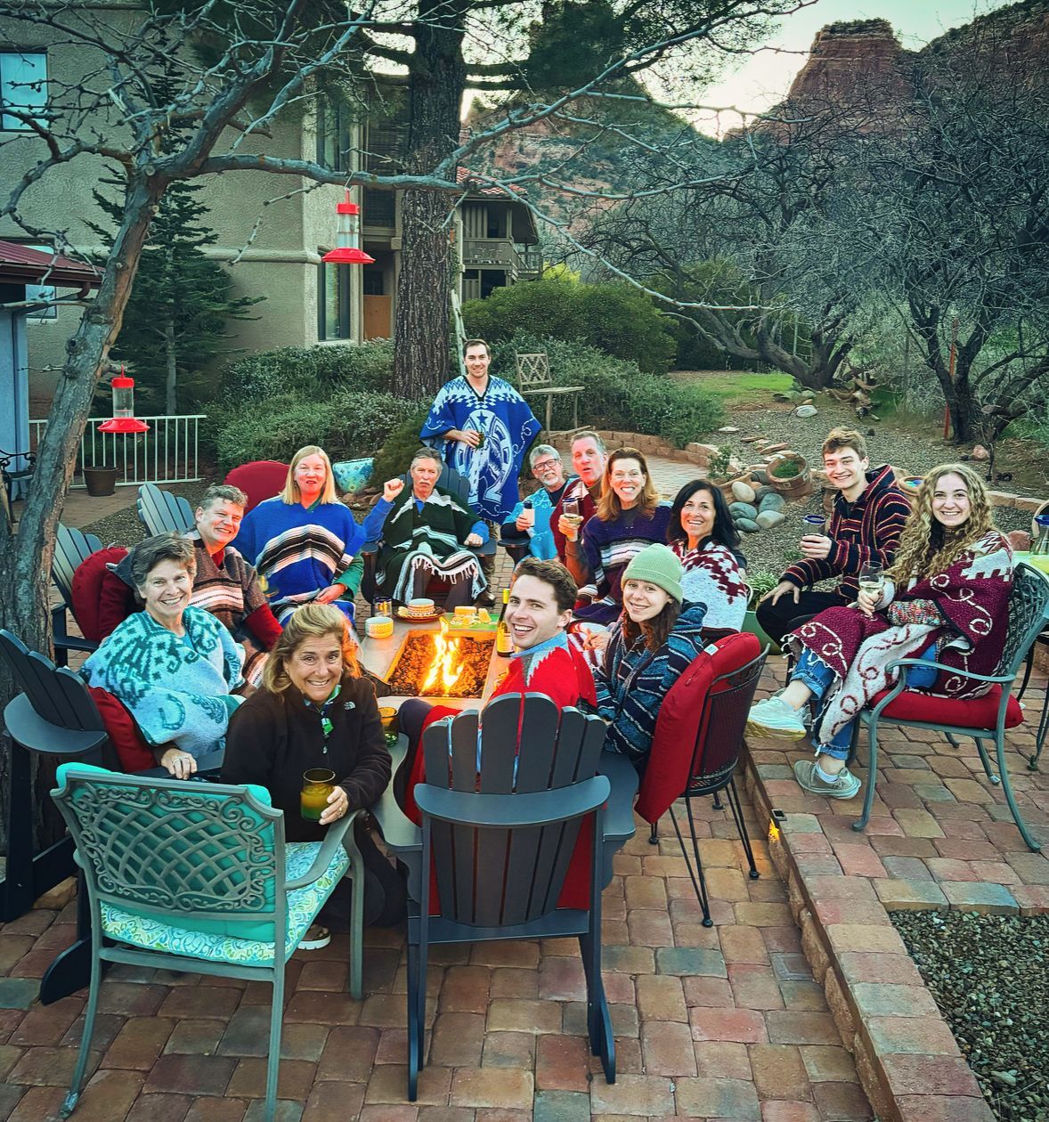 A group of people are sitting around a table in front of a fire