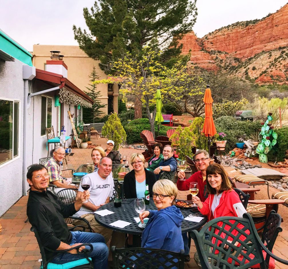 A group of people are sitting around a table drinking wine.