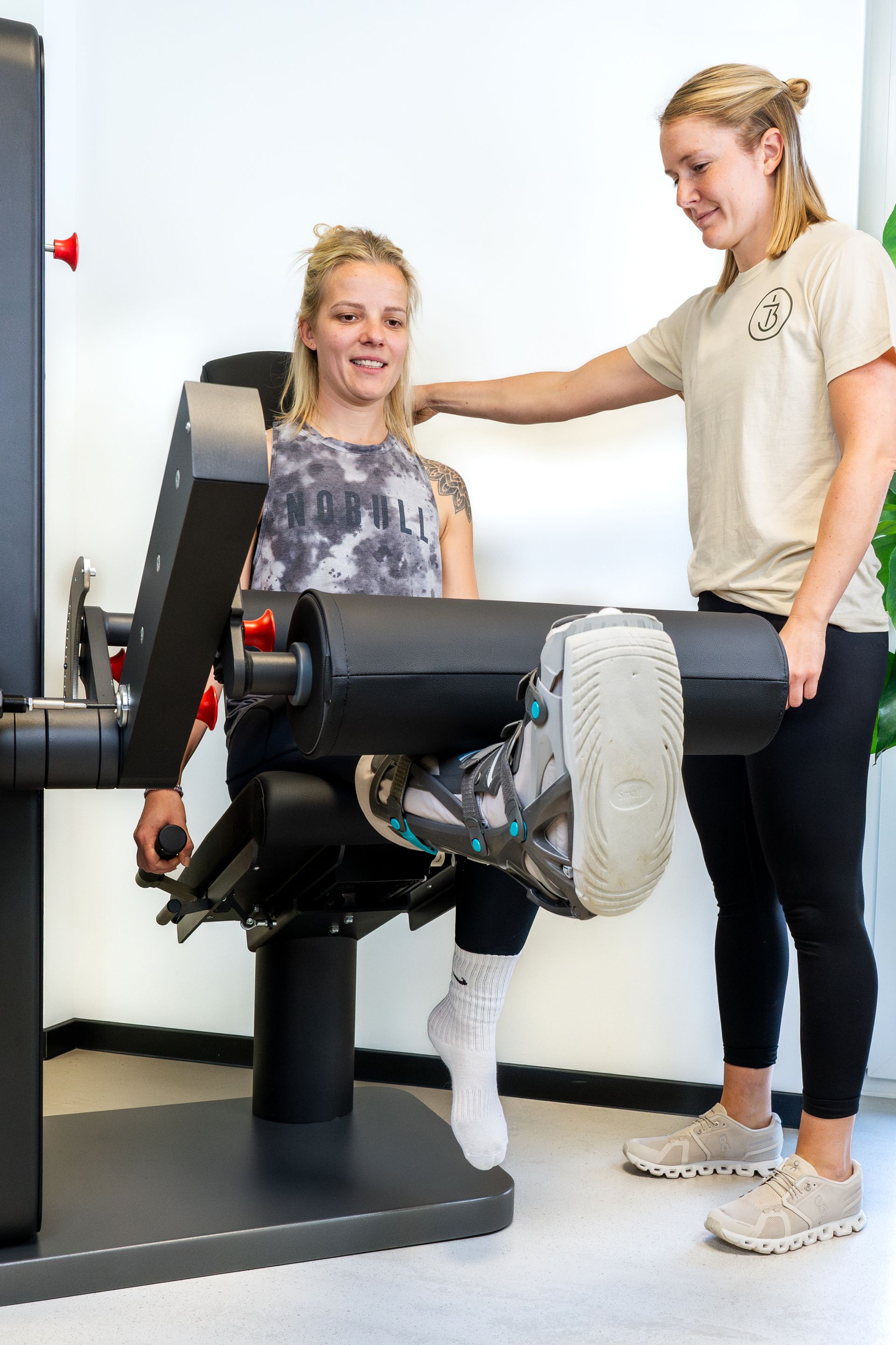 Eine Frau hilft einer anderen Frau bei der Benutzung eines Geräts in einem Fitnessstudio.