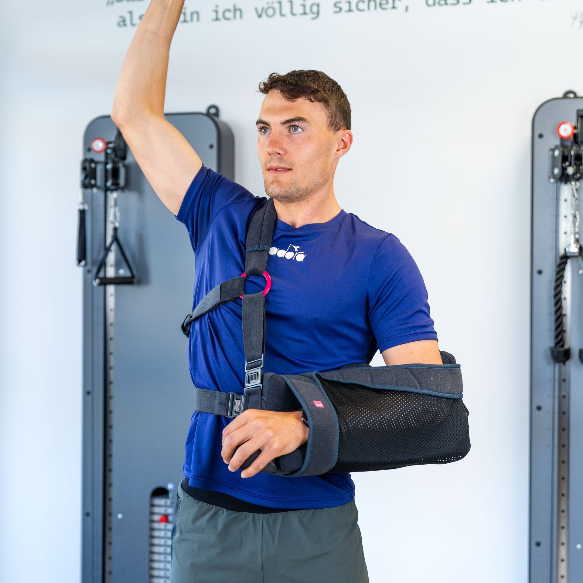 Ein Mann in einem blauen Shirt mit dem Arm in einer schwarze Armschlinge