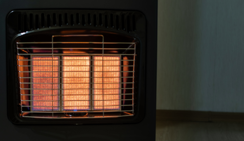 Glowing electric space heater with safety grill on in a dim room