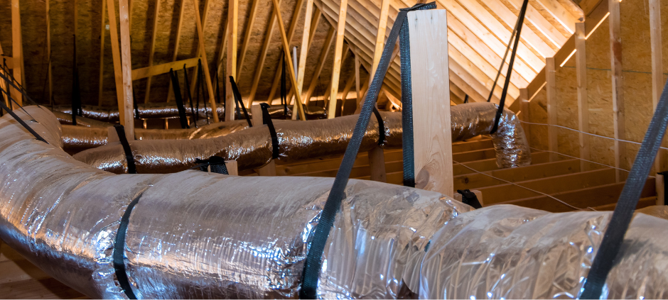 Flexible silver insulated air ducts suspended by black straps in a wooden unfinished attic crawl space.