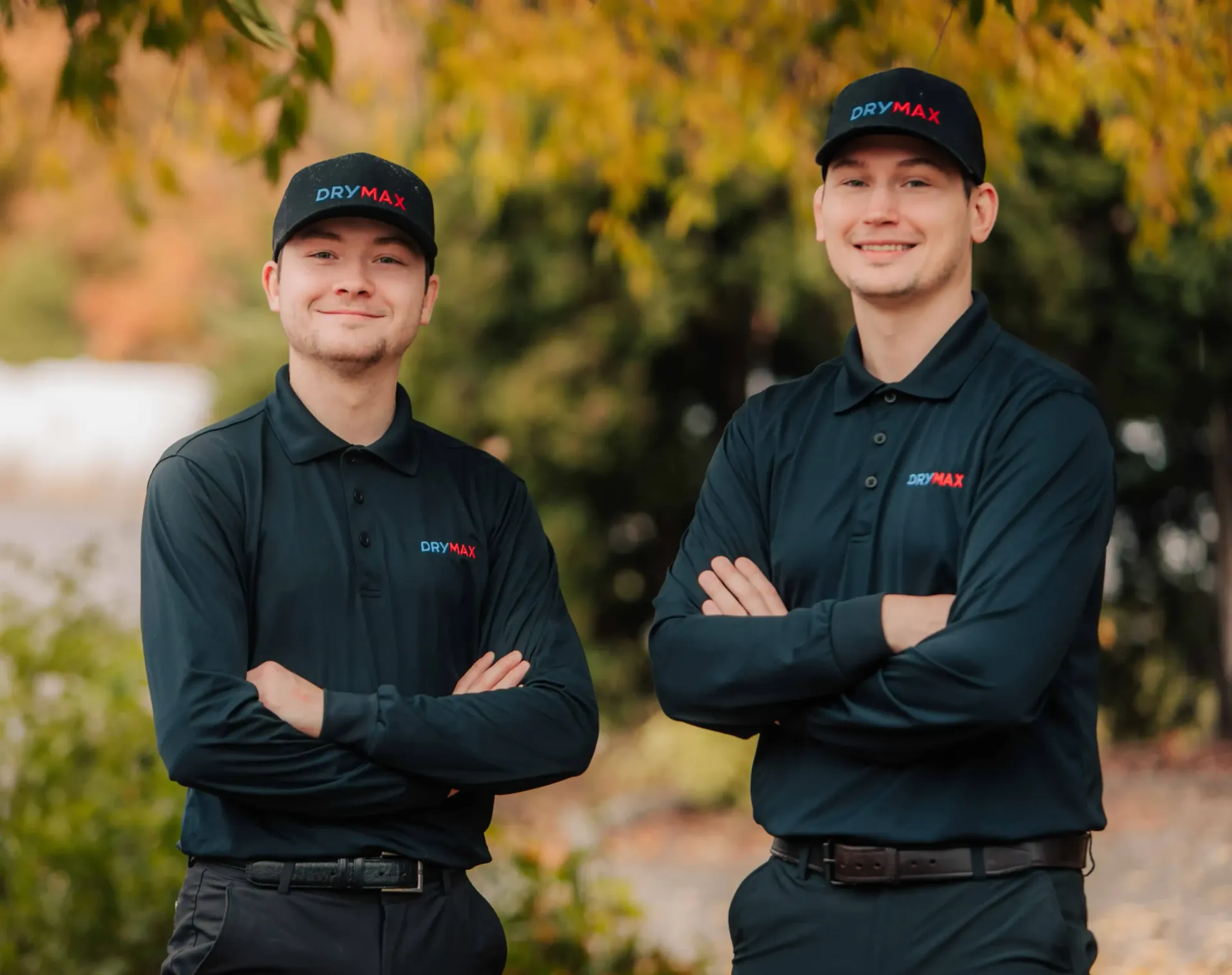 Two men are standing next to each other with their arms crossed.