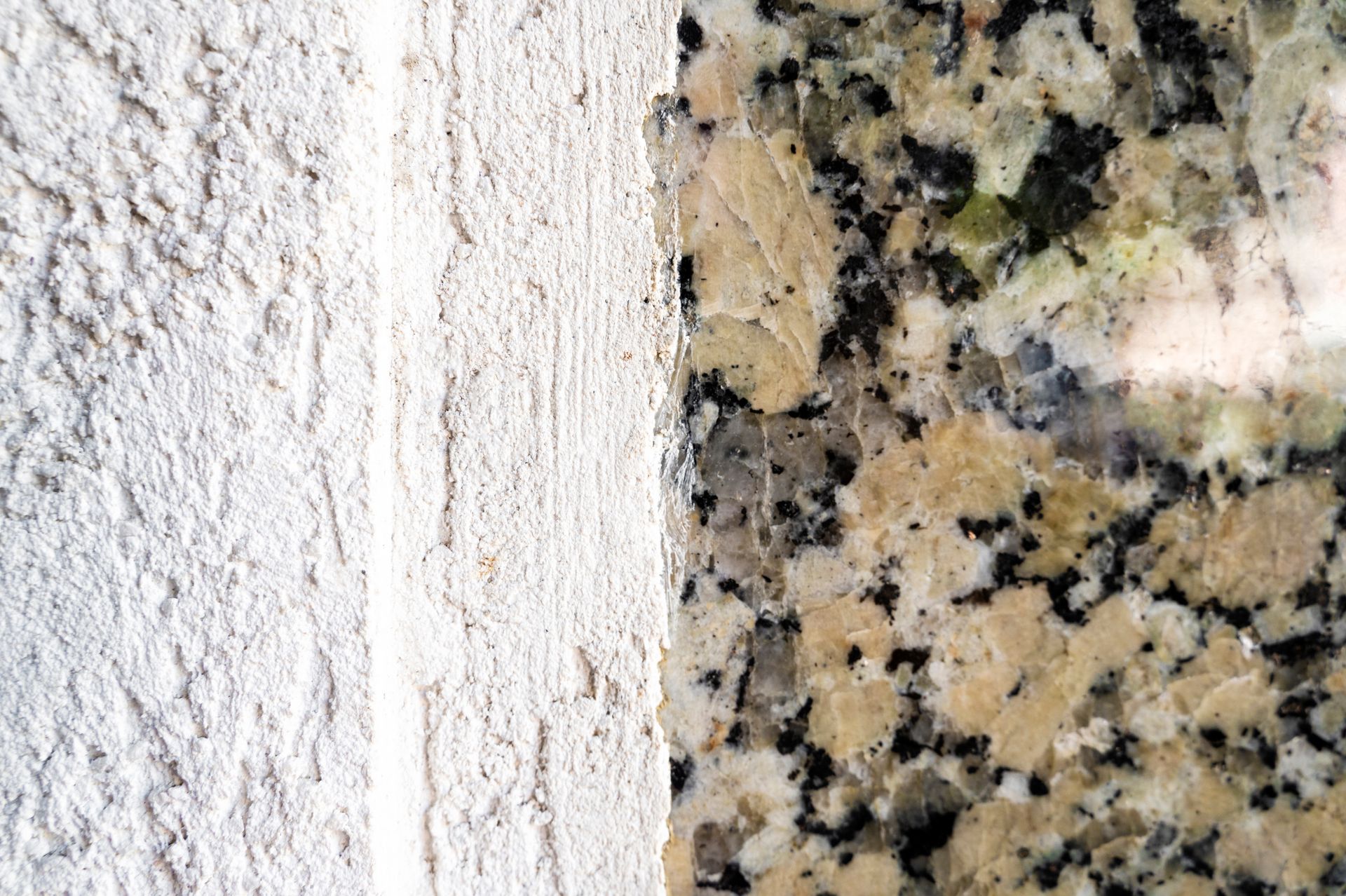 A close up of a granite counter top next to a white wall.