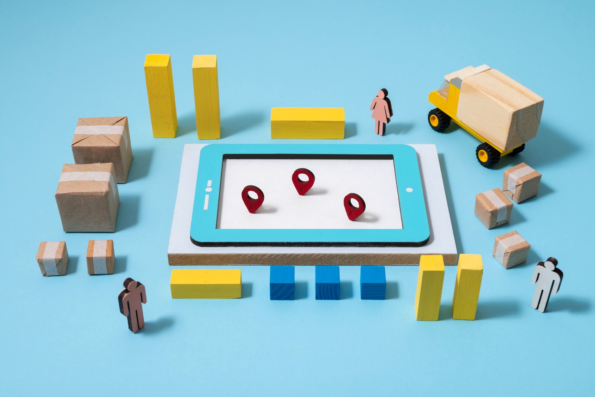 A tablet with a map on it is surrounded by wooden blocks and a truck.