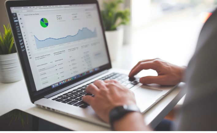 Person typing on a laptop showing a dashboard with charts and data analytics