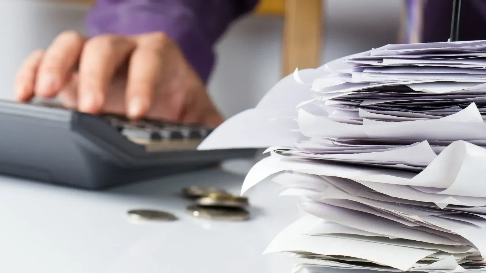 a person using a calculator in front of a pile of documents