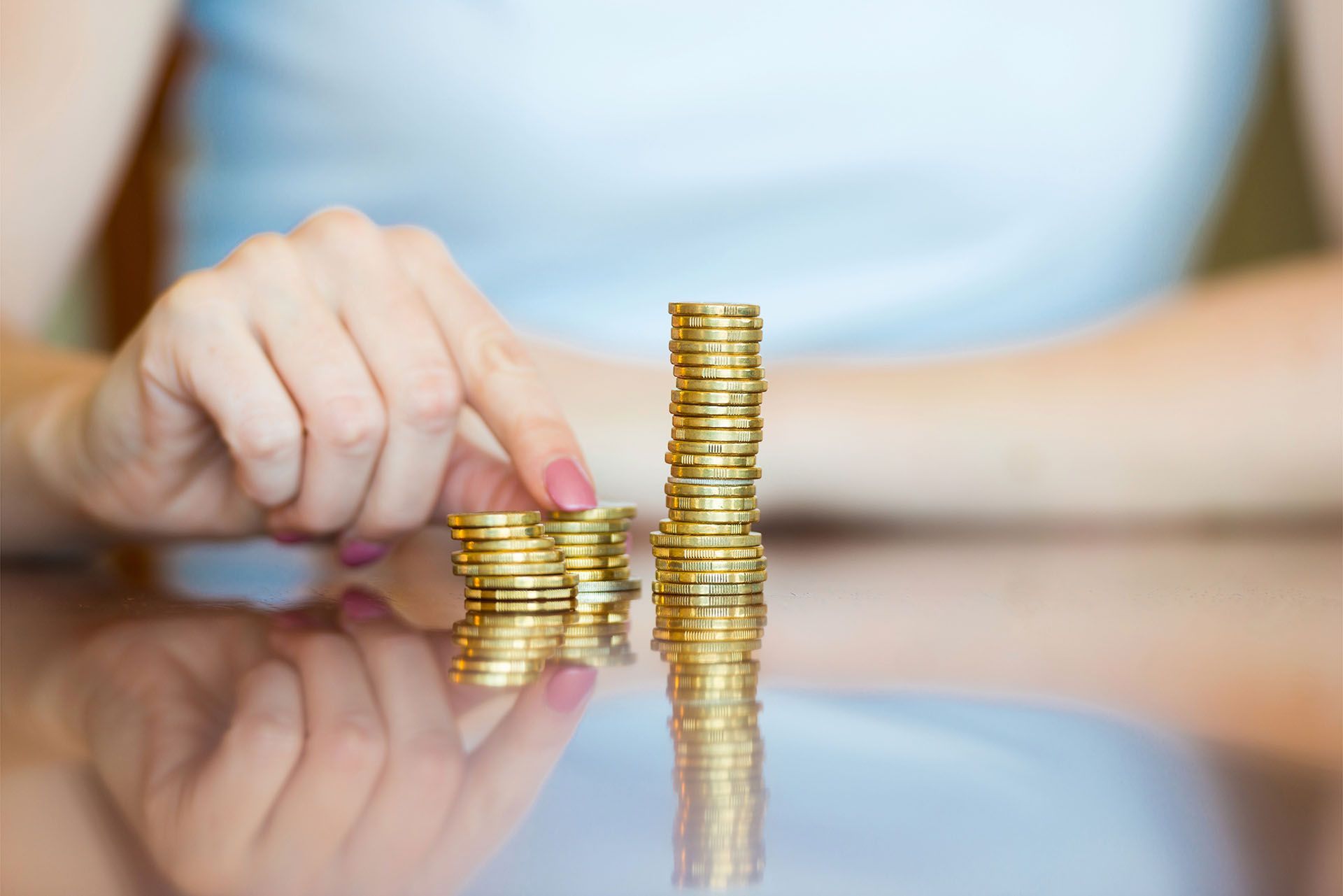 A woman is stacking coins on top of each other on a table.